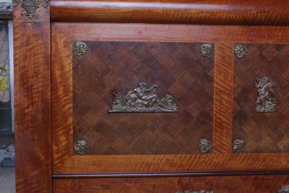 An Empire style mahogany double bedstead featuring rolled headboard profiles, parquetry panelwork, and decorative gilt-bronze mounts. View X