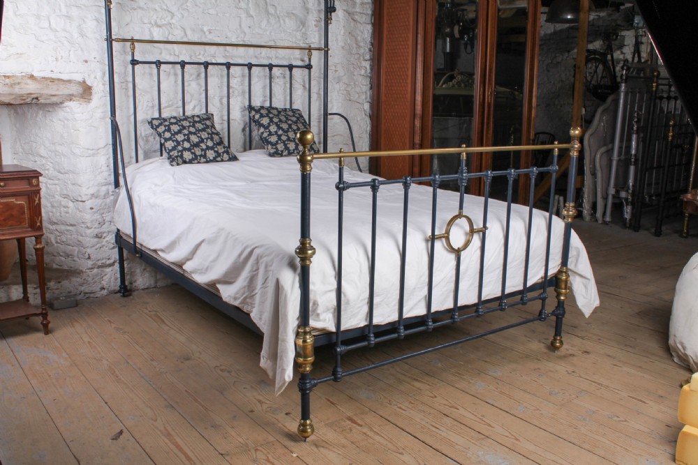 A Victorian black iron and brass king size half tester bed featuring vertical spindles and turned brass finials. View II
