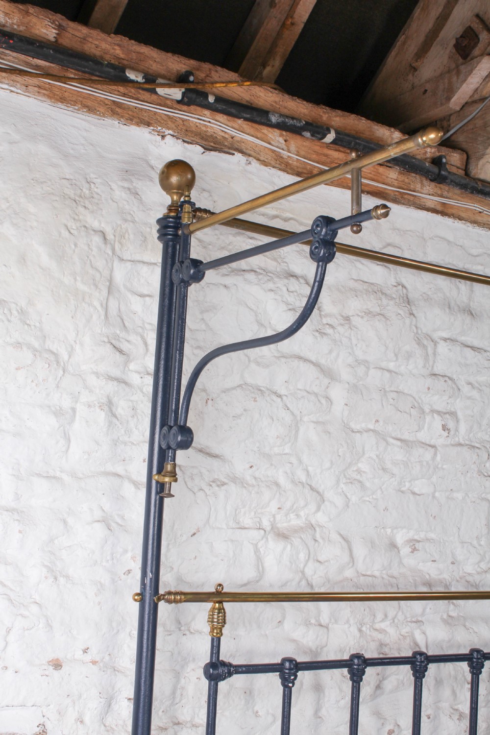 A Victorian black iron and brass king size half tester bed featuring vertical spindles and turned brass finials. View IV