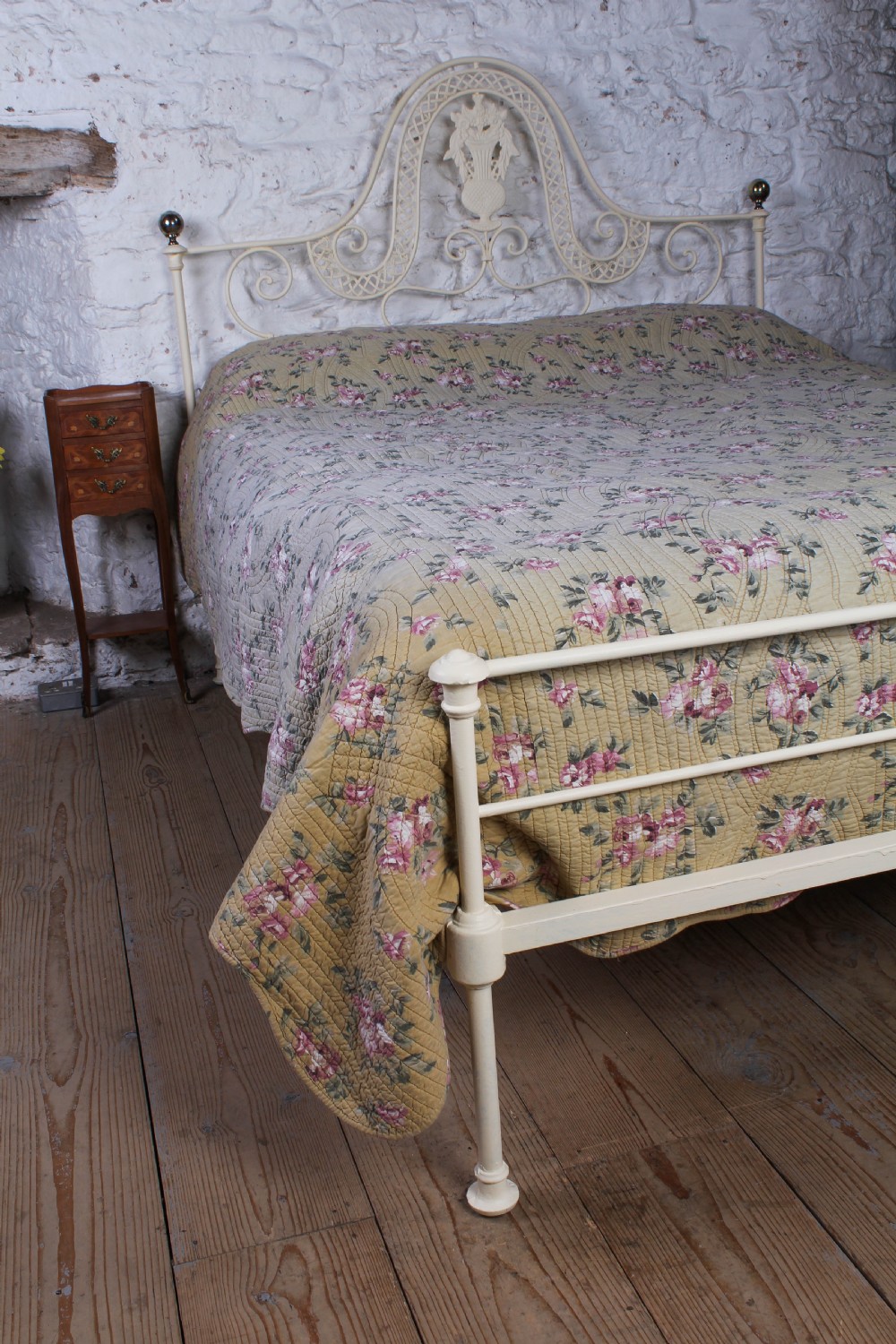 A king-size cream painted forged iron bedstead featuring an arched scrollwork headboard with a central decorative crest and a low footboard. View VII