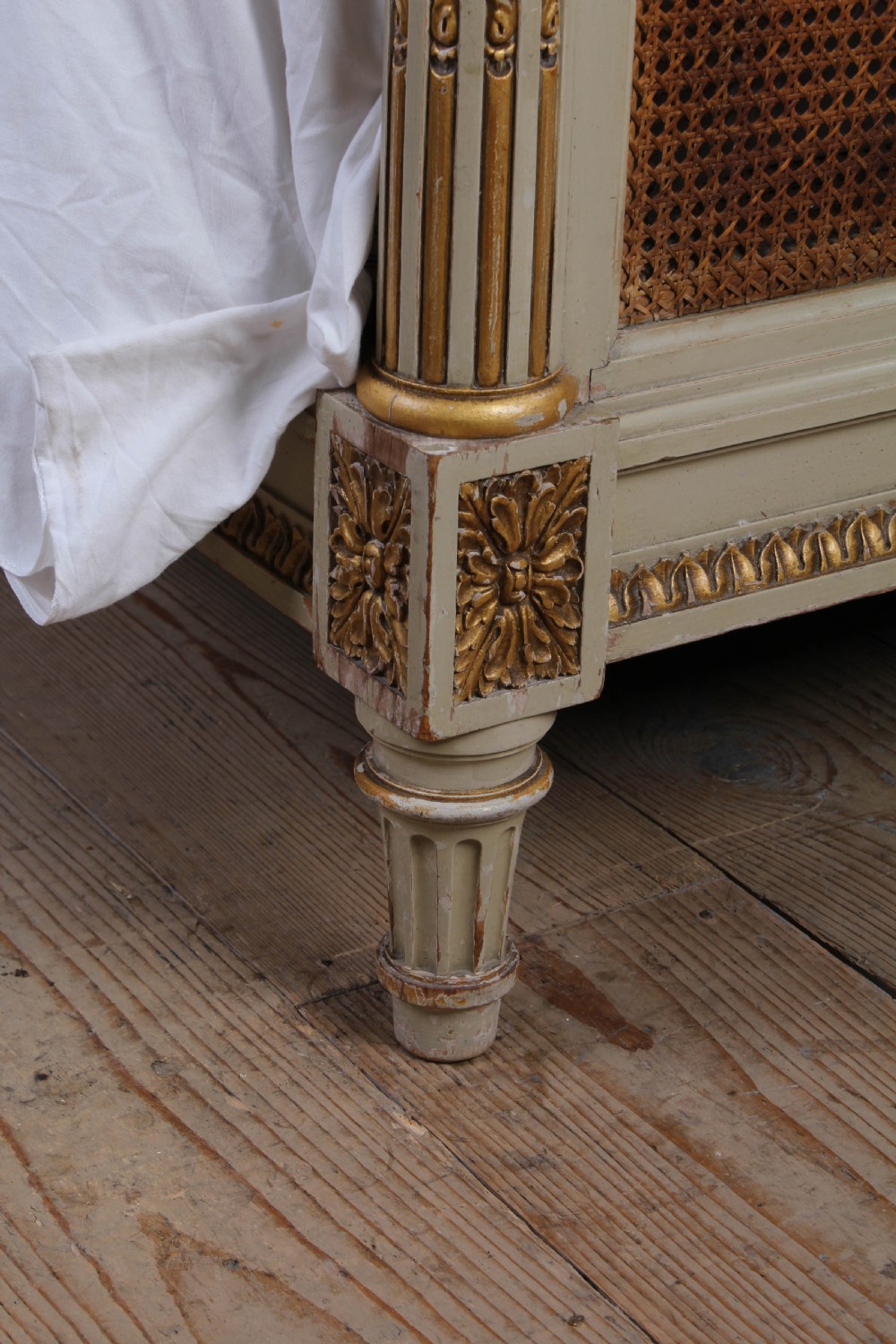 A French Louis XVI style king size bedstead featuring cream painted and gilded carved wood with natural woven cane panels on the headboard and footboard. View VI