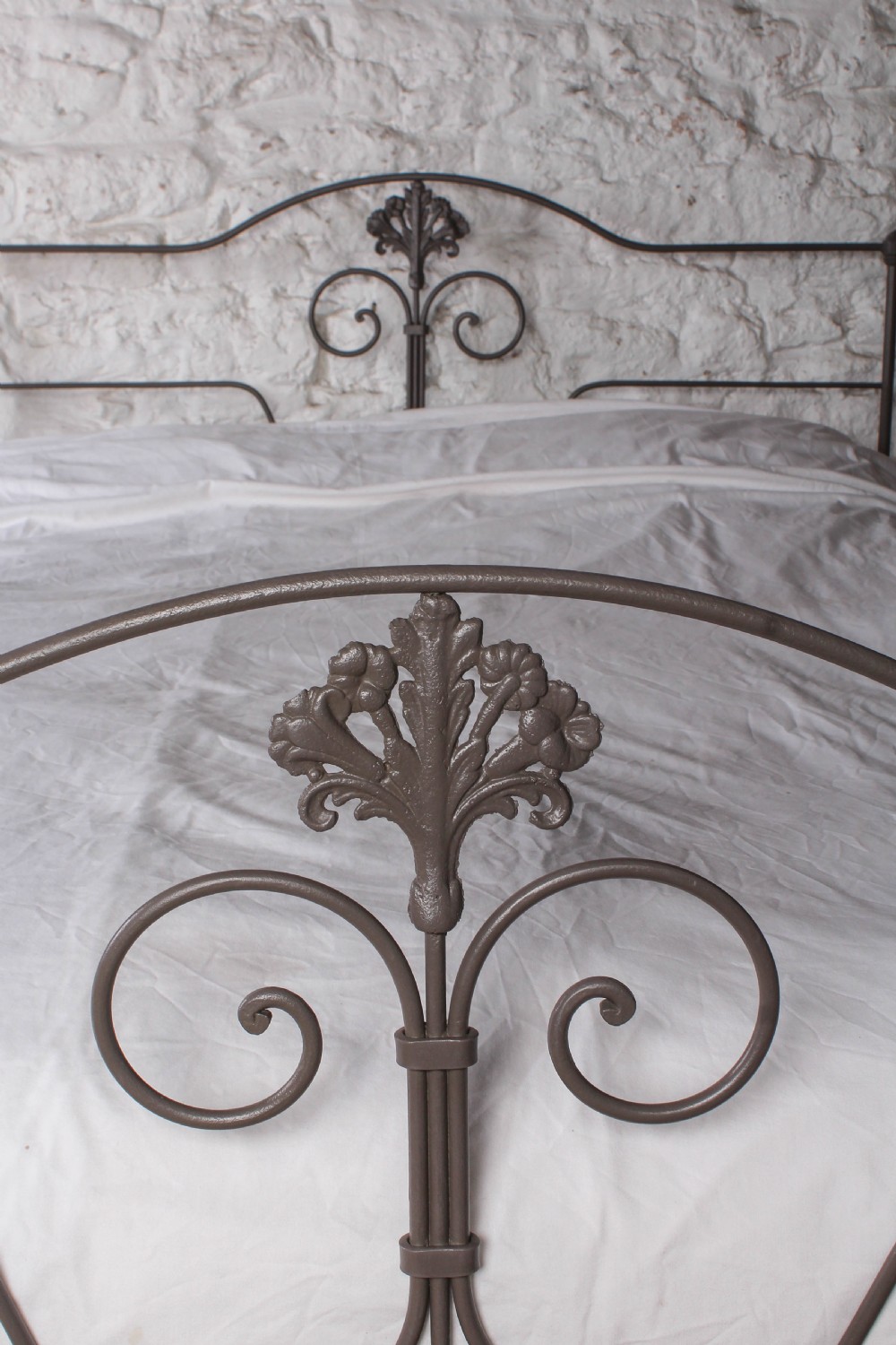A king size Portuguese iron bed frame painted in a neutral taupe colour, featuring decorative scrollwork and a central shell motif on both the headboard and footboard. View II