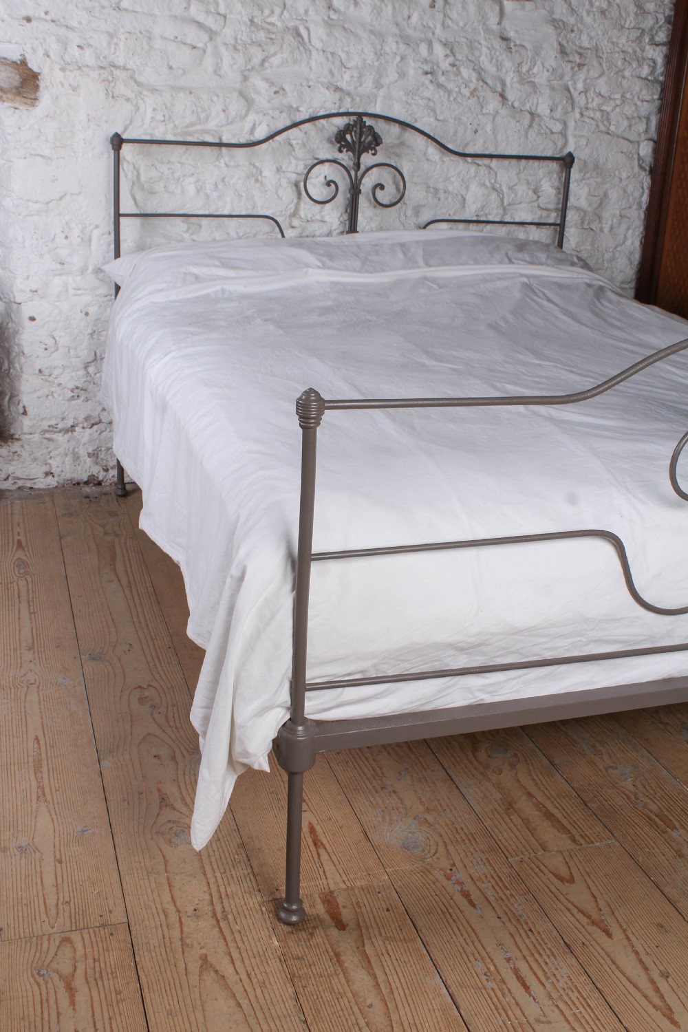 A king size Portuguese iron bed frame painted in a neutral taupe colour, featuring decorative scrollwork and a central shell motif on both the headboard and footboard. View VI