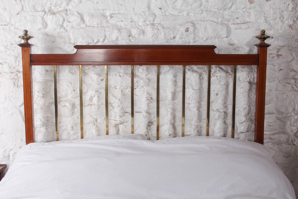 An antique mahogany double bed frame featuring polished brass upright spindles, brass urn finials, and an oval marquetry medallion inlaid on the footboard. View V