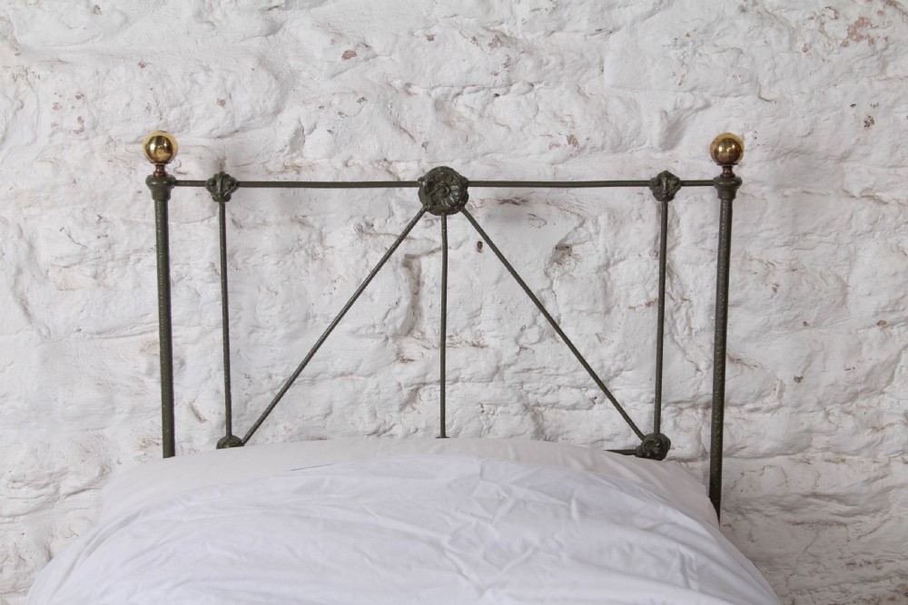 A small Victorian single platform bed constructed from dark green painted iron with brass corner finials. View IV