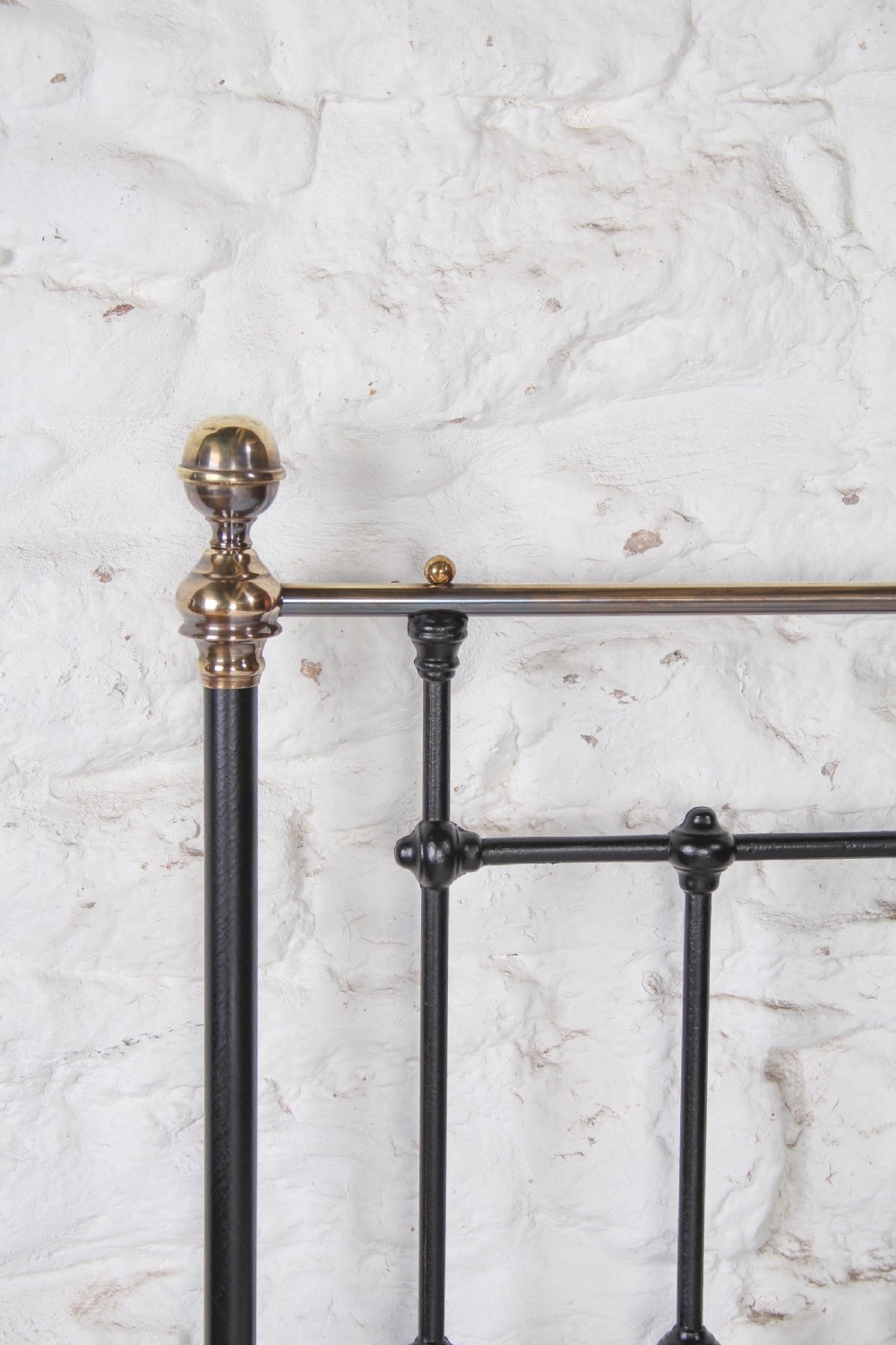 A Victorian single cast iron bedstead with black vertical spindles, brass finials, and white bed linen. View IV