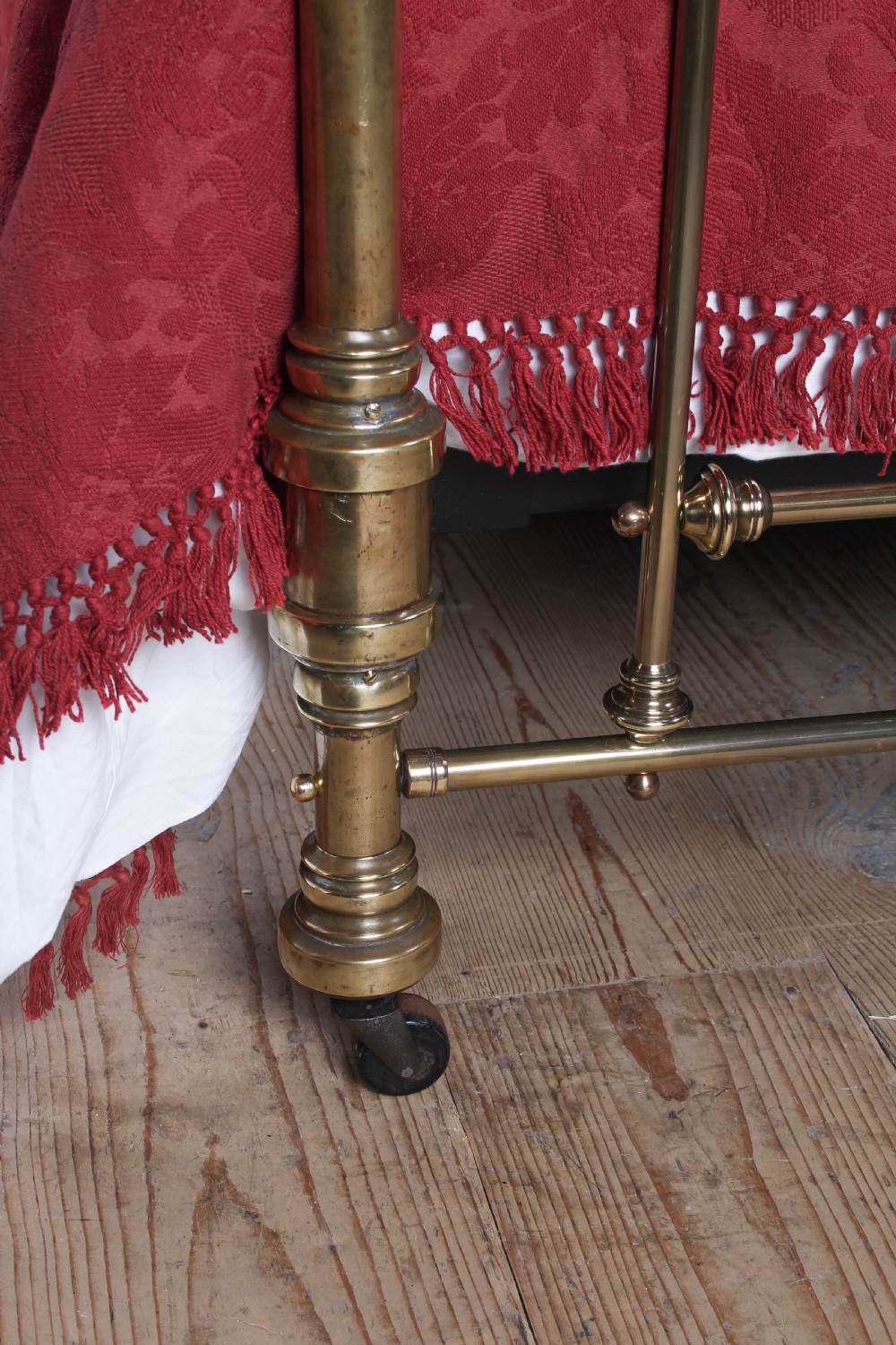 An antique king-sized brass bedstead featuring turned vertical spindles, corner post finials, and a warm aged patina. View IV