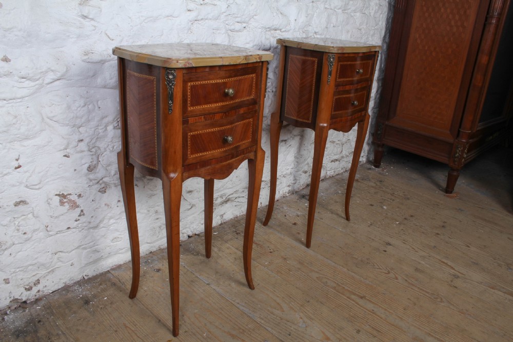 A pair of slender French wooden bedside tables featuring variegated marble tops, two inlaid drawers, and high cabriole legs. View V