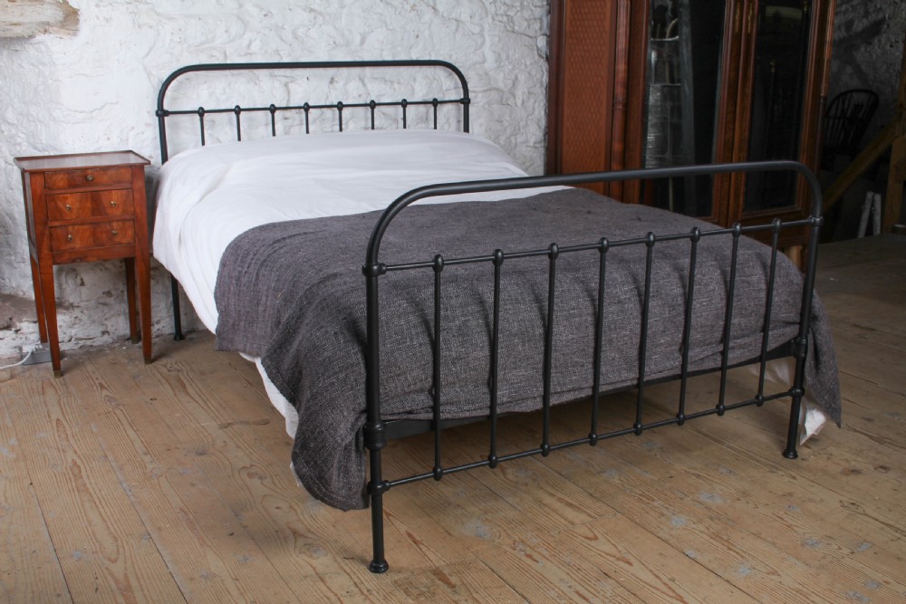 A black painted iron double bed frame featuring a vertical spindle headboard and matching footboard.