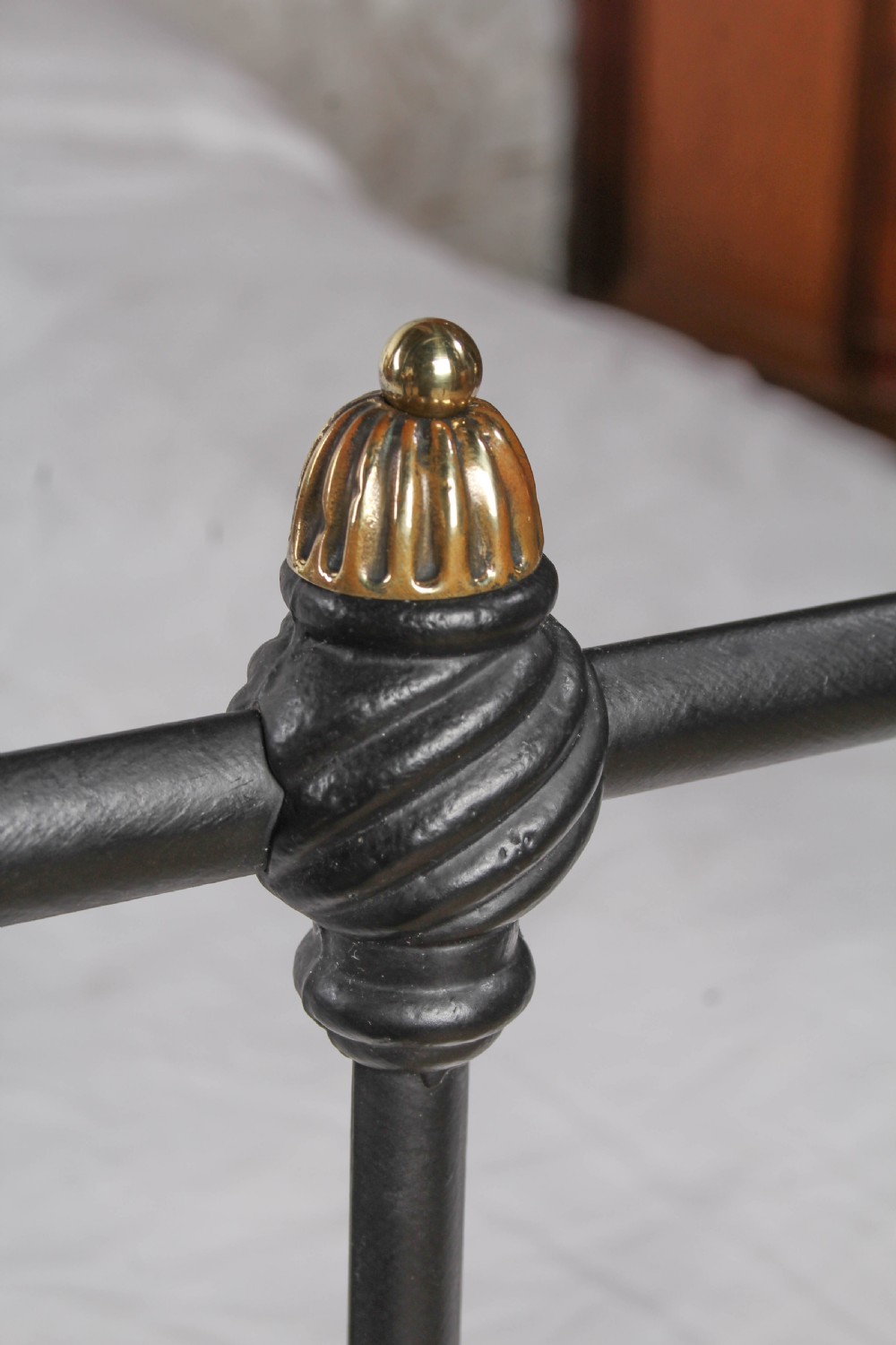 A black iron double bed frame with vertical upright spindles and decorative brass finial accents. View III