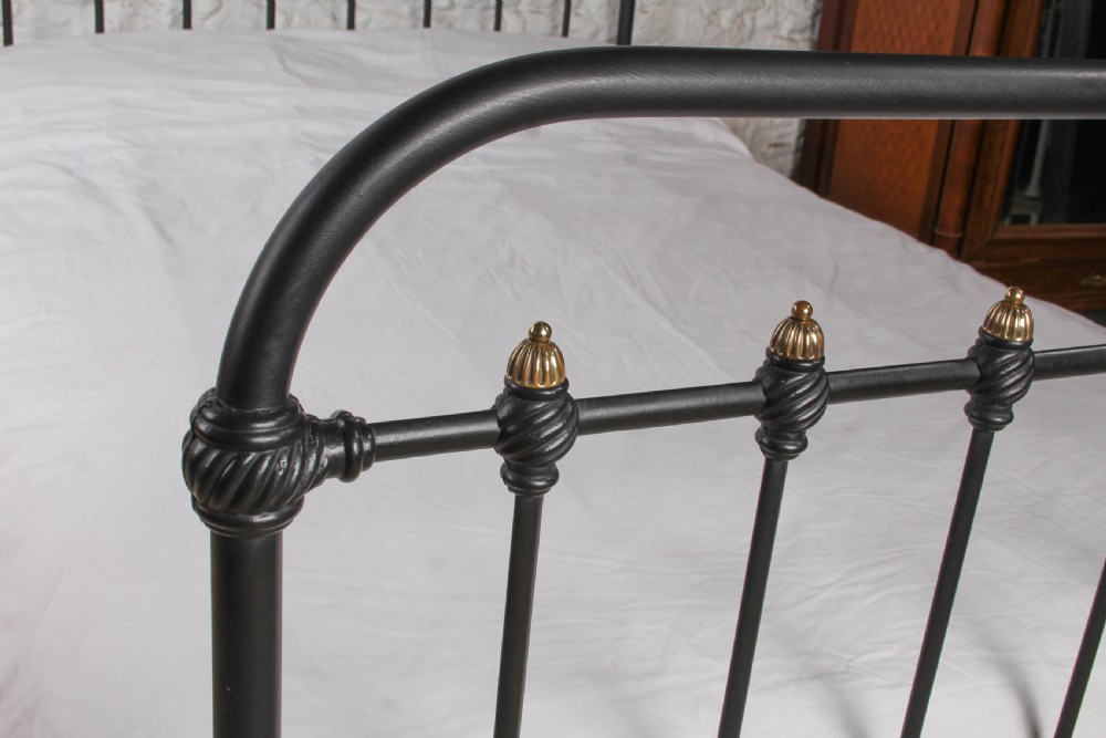 A black iron double bed frame with vertical upright spindles and decorative brass finial accents. View IV
