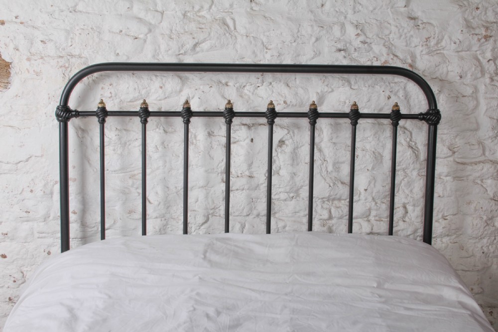 A black iron double bed frame with vertical upright spindles and decorative brass finial accents. View V