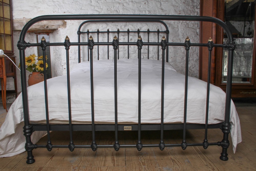 A black iron double bed frame with vertical upright spindles and decorative brass finial accents. View VI