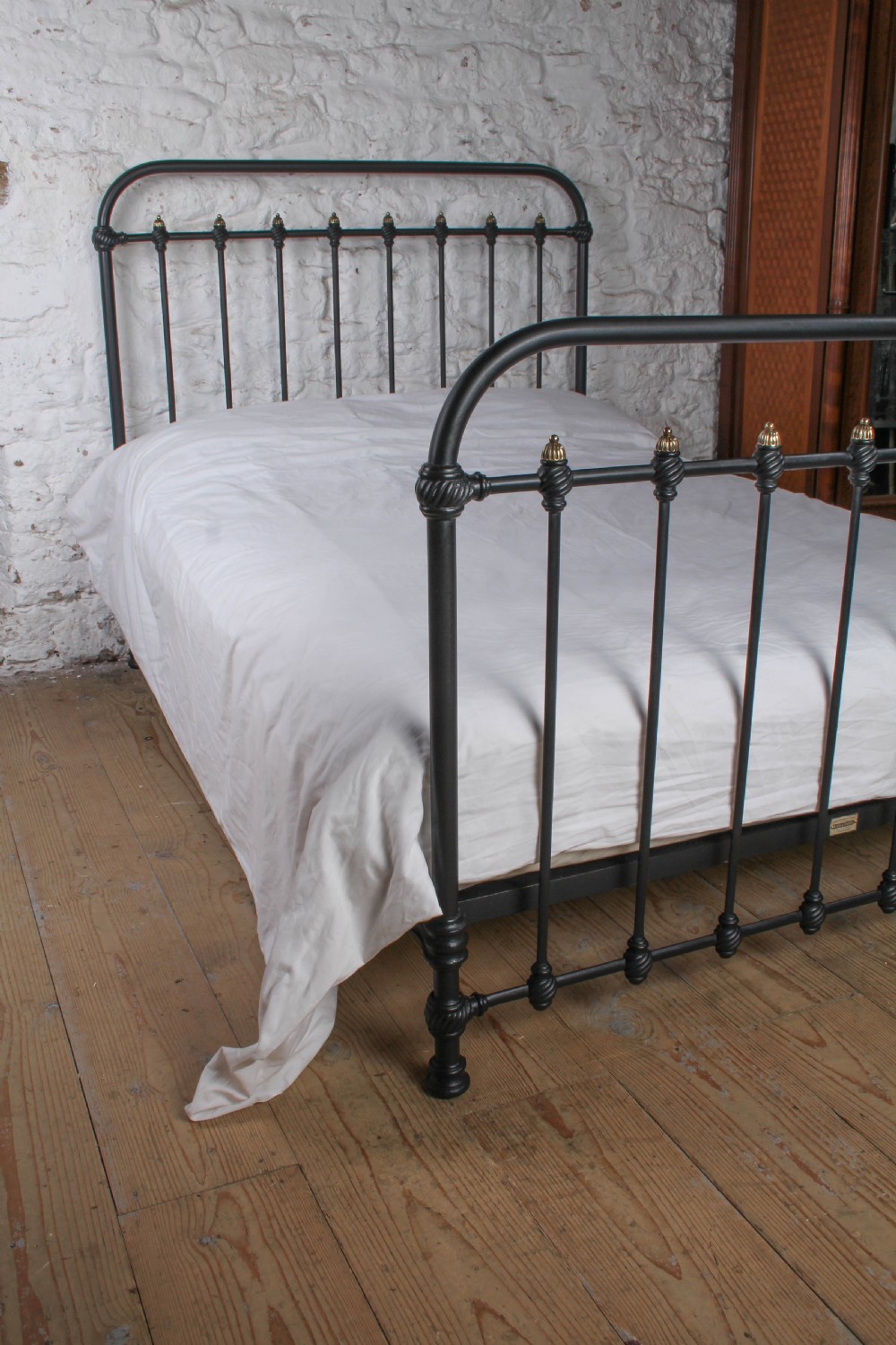 A black iron double bed frame with vertical upright spindles and decorative brass finial accents. View VII