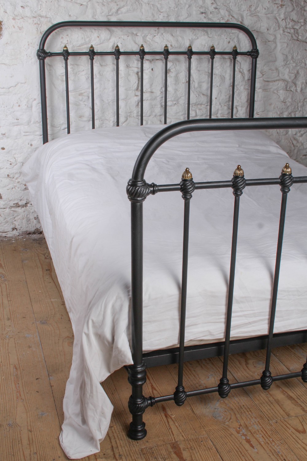 A black iron double bed frame with vertical upright spindles and decorative brass finial accents. View VIII