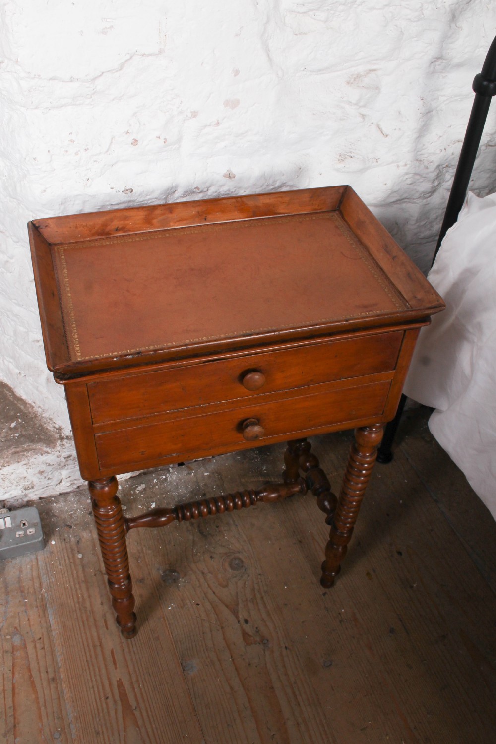 An antique warm brown wooden side table featuring bobbin-turned legs, a tray top, two drawers with round wooden knobs, and a turned stretcher. View II