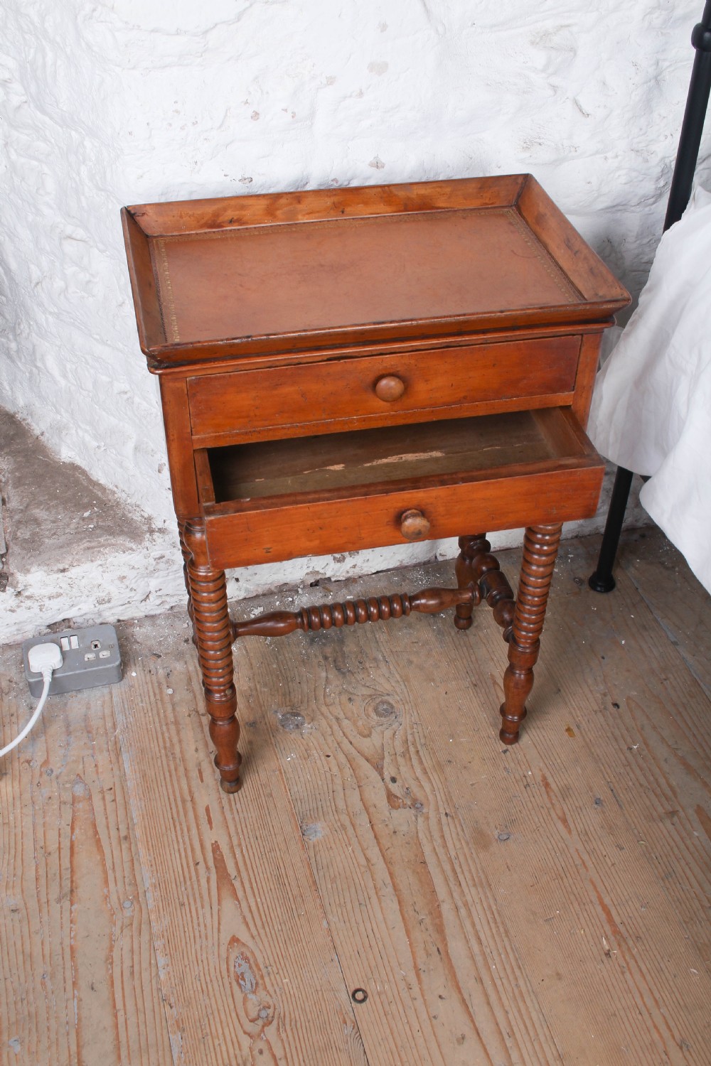 An antique warm brown wooden side table featuring bobbin-turned legs, a tray top, two drawers with round wooden knobs, and a turned stretcher. View V