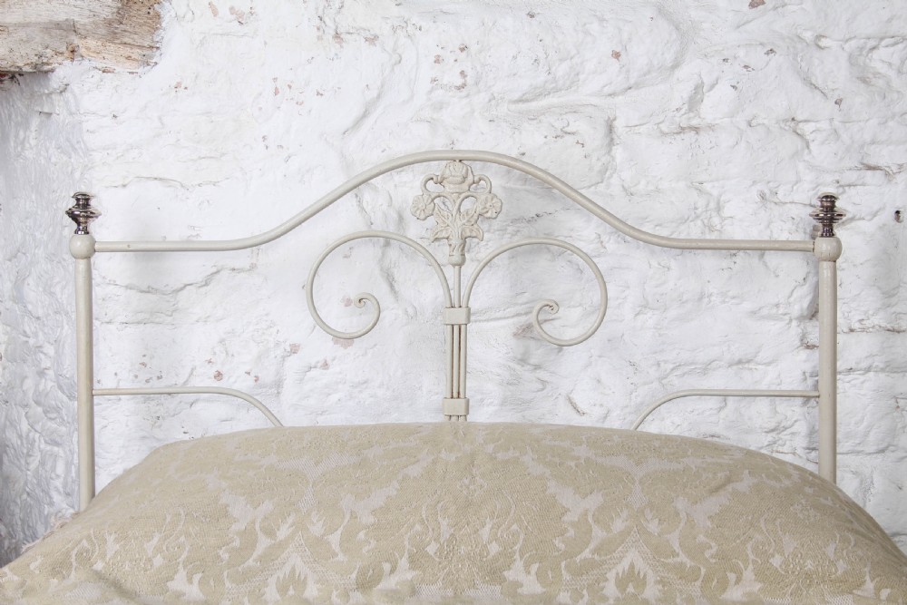 A pair of cream-painted antique Portuguese iron single beds featuring decorative scrolled headboards and low-profile foot ends. View II
