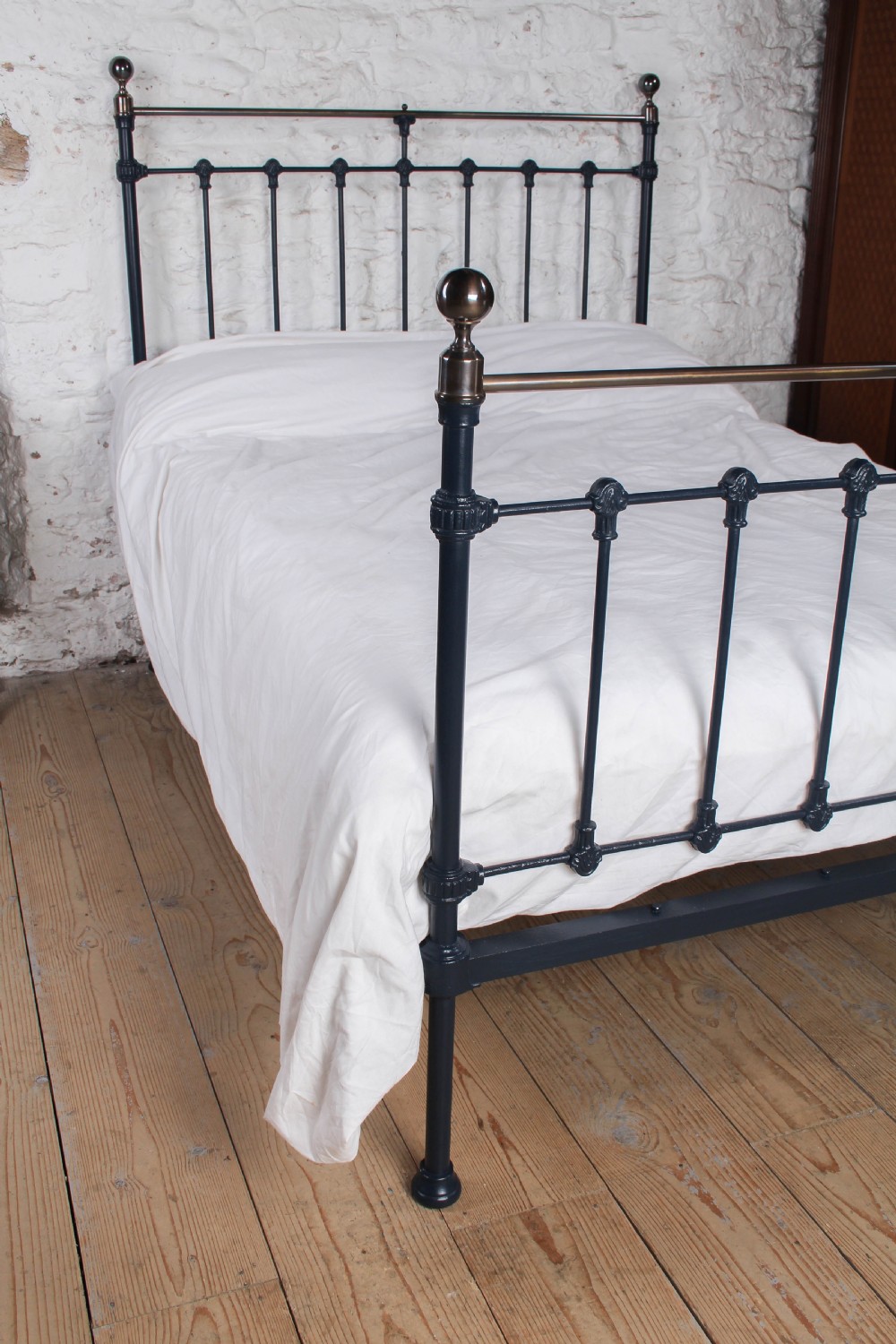 An Edwardian iron and brass double bedstead featuring dark vertical spindles, decorative cast collars, and polished brass top rails with brass finials. View II