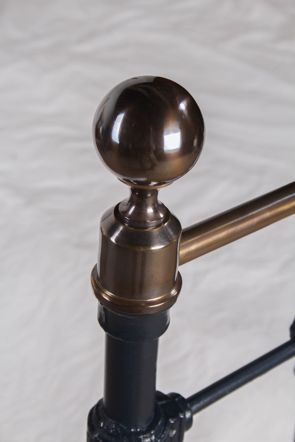 An Edwardian iron and brass double bedstead featuring dark vertical spindles, decorative cast collars, and polished brass top rails with brass finials. View IV