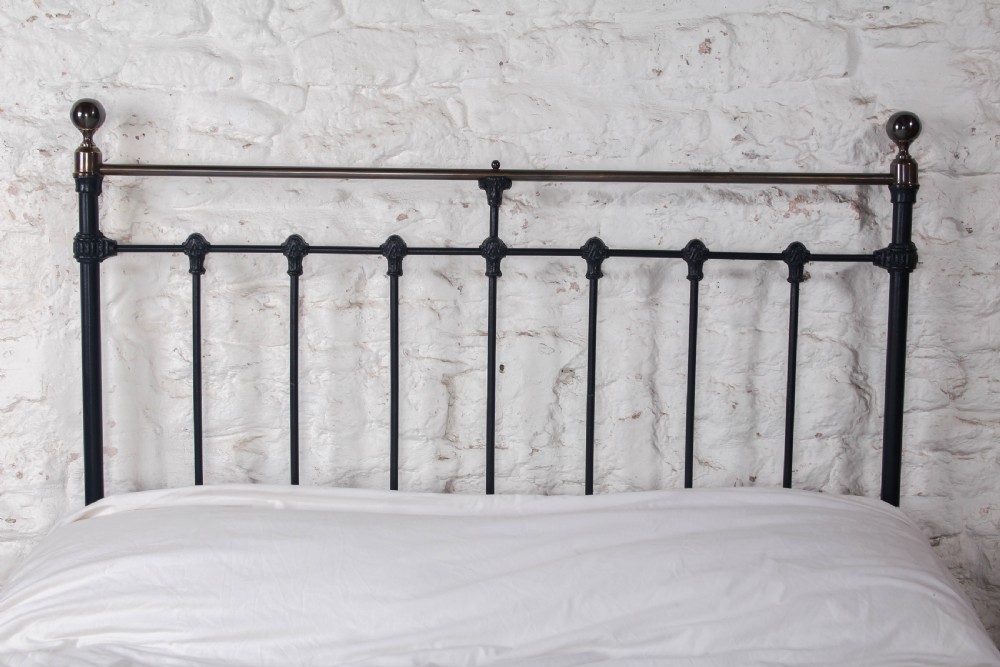 An Edwardian iron and brass double bedstead featuring dark vertical spindles, decorative cast collars, and polished brass top rails with brass finials. View V