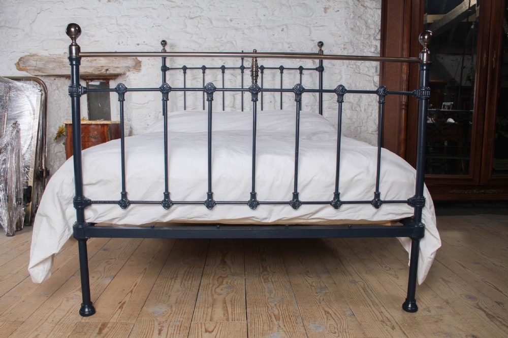 An Edwardian iron and brass double bedstead featuring dark vertical spindles, decorative cast collars, and polished brass top rails with brass finials. View VI
