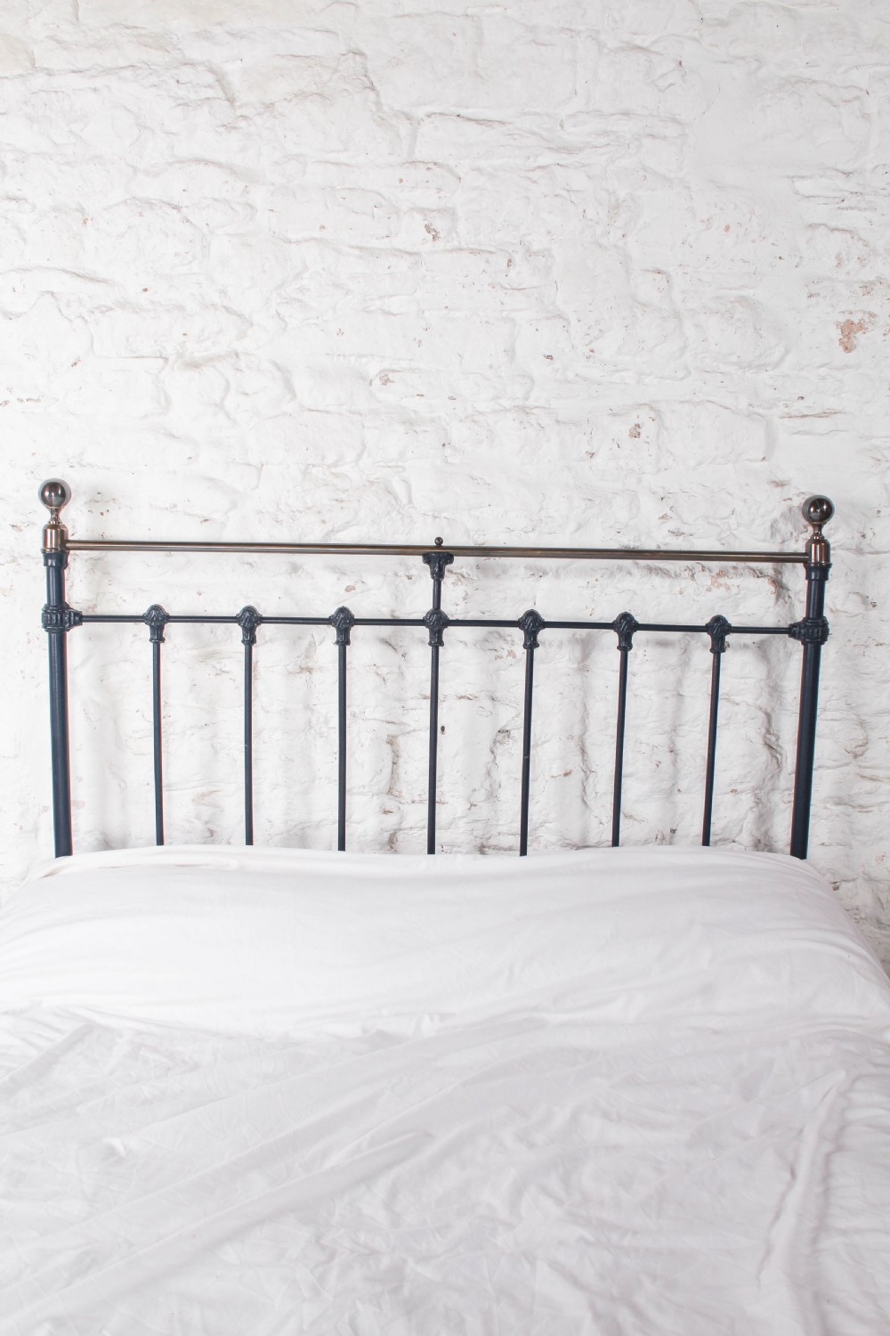 An Edwardian iron and brass double bedstead featuring dark vertical spindles, decorative cast collars, and polished brass top rails with brass finials. View VII