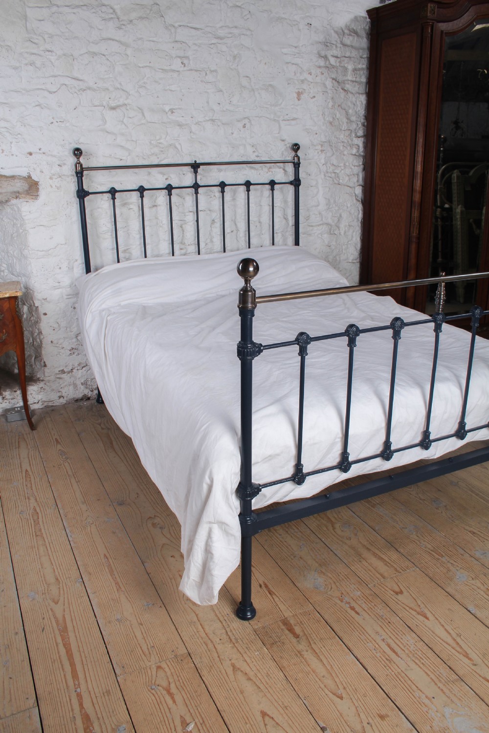 An Edwardian iron and brass double bedstead featuring dark vertical spindles, decorative cast collars, and polished brass top rails with brass finials. View VIII