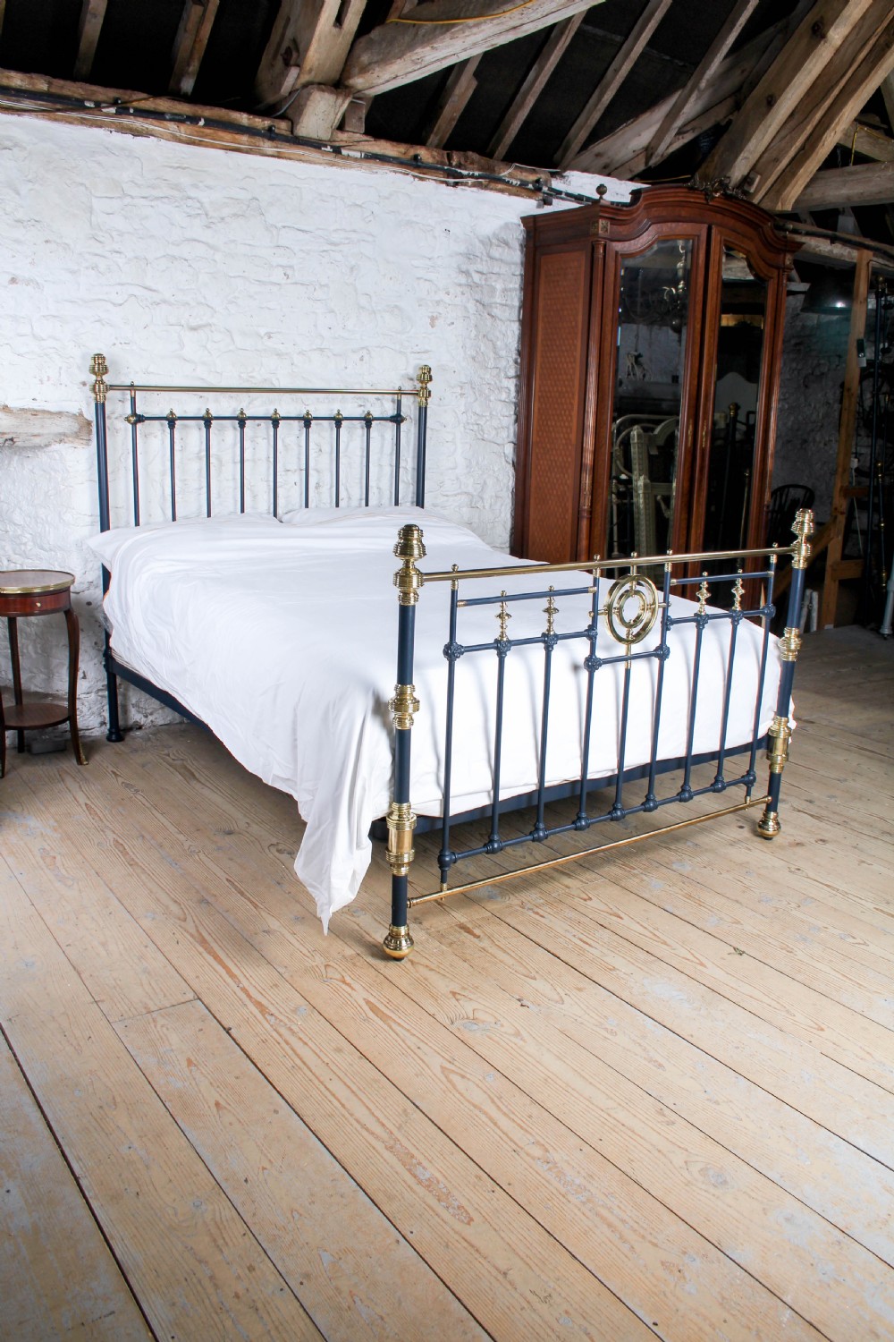 A Victorian king size bedstead crafted from black iron with polished brass rails, finials, and a central circular brass motif. View II