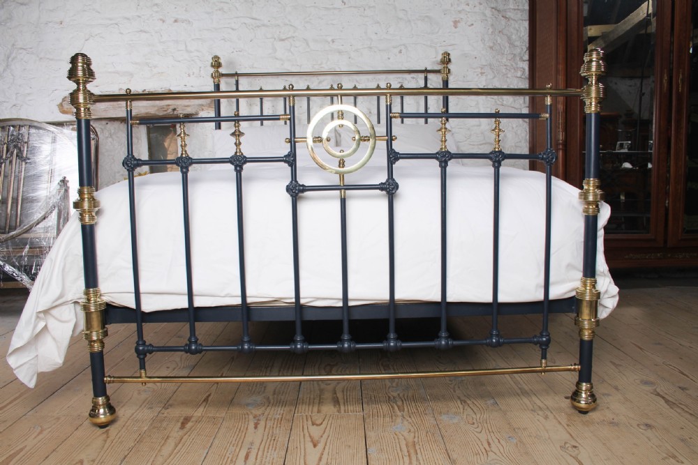 A Victorian king size bedstead crafted from black iron with polished brass rails, finials, and a central circular brass motif. View V