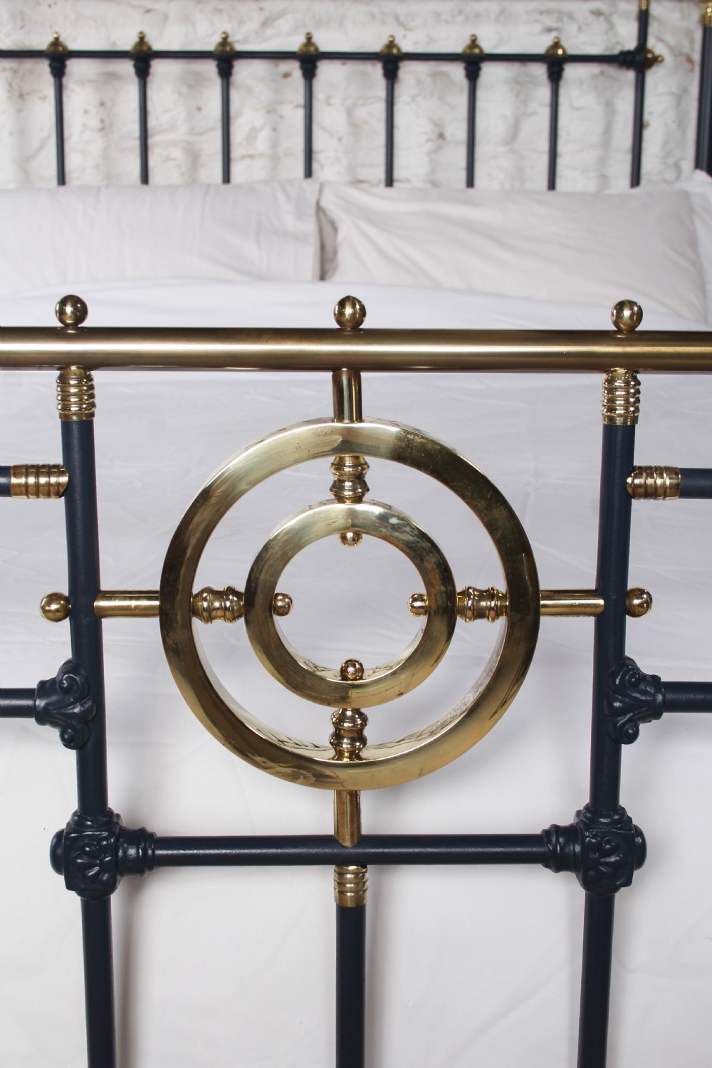 A Victorian king size bedstead crafted from black iron with polished brass rails, finials, and a central circular brass motif. View VI