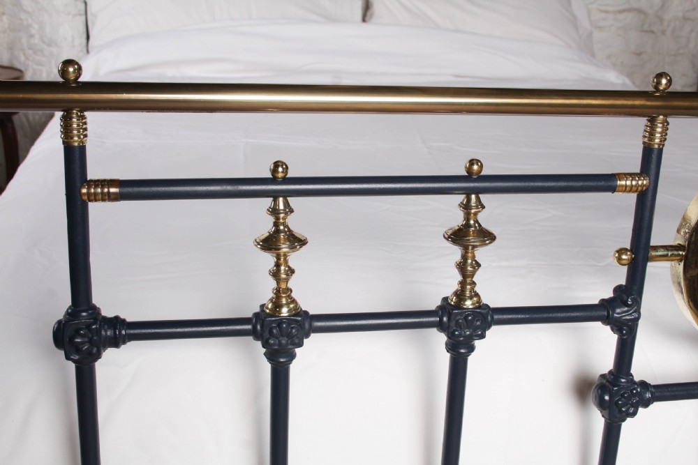 A Victorian king size bedstead crafted from black iron with polished brass rails, finials, and a central circular brass motif. View VII