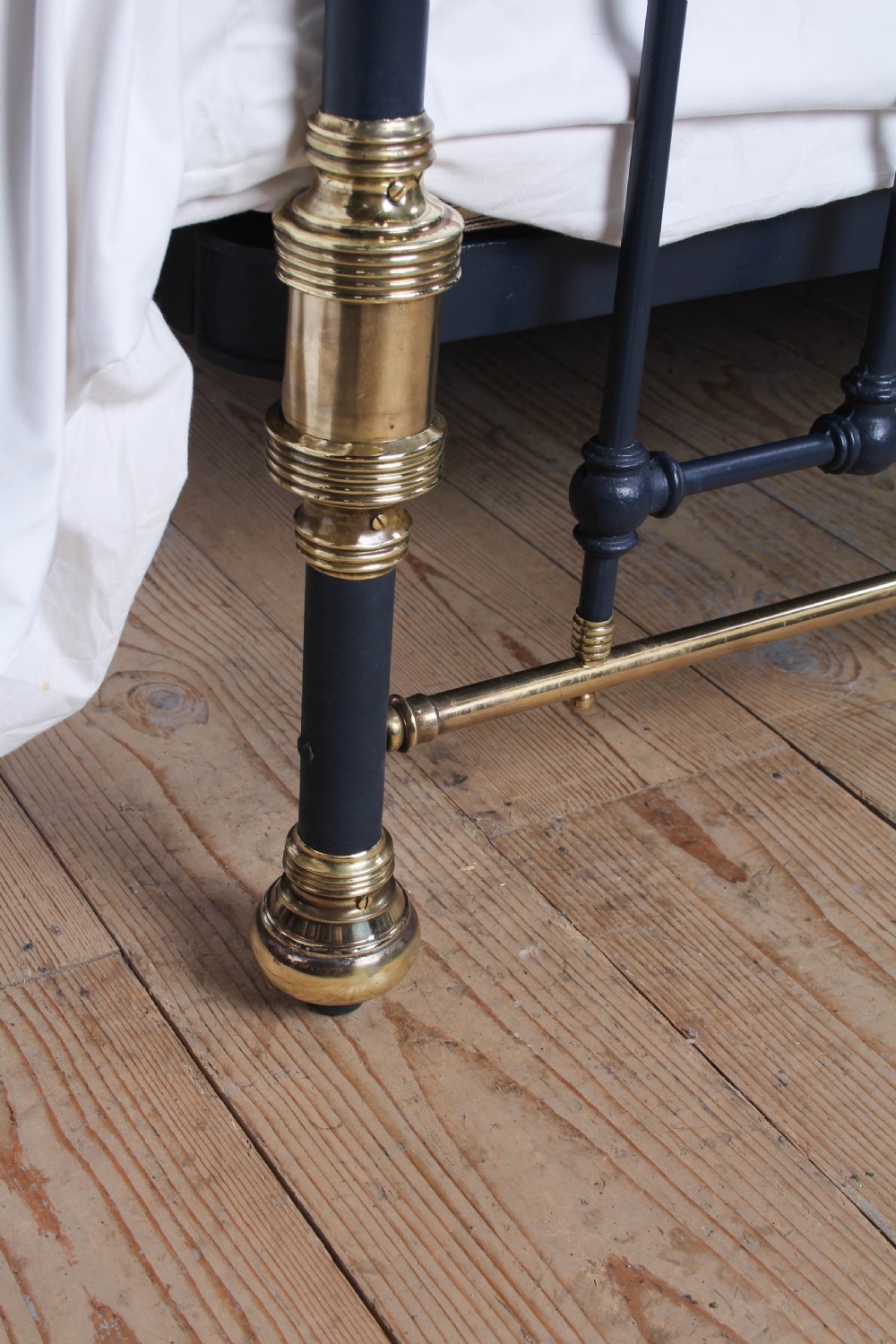 A Victorian king size bedstead crafted from black iron with polished brass rails, finials, and a central circular brass motif. View IX