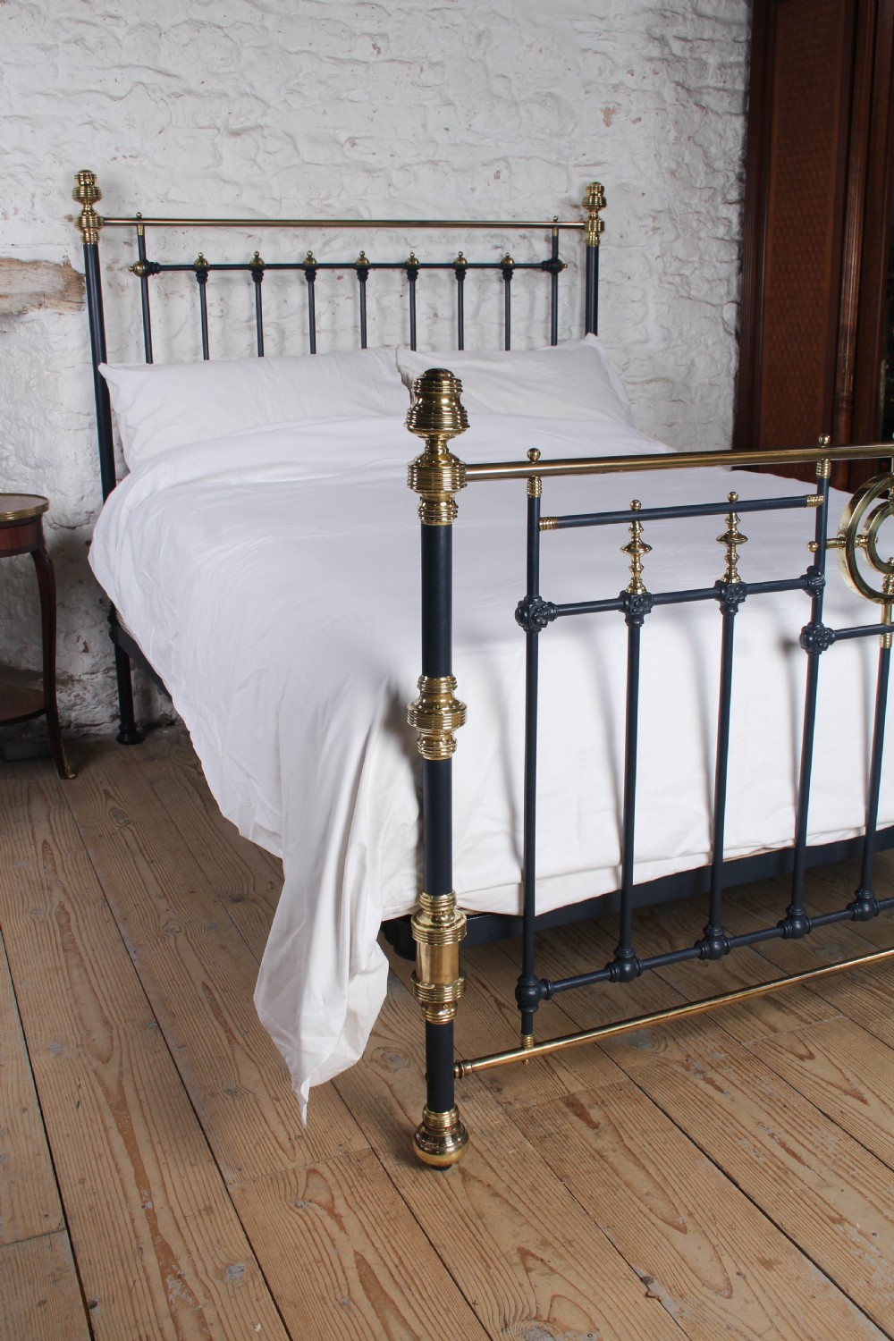 A Victorian king size bedstead crafted from black iron with polished brass rails, finials, and a central circular brass motif. View X