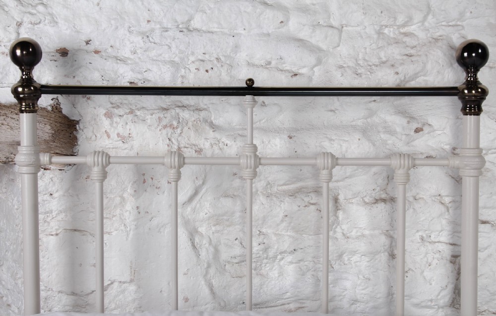 A pair of white painted Victorian single bed frames with vertical iron spindles and brass top rails. View V