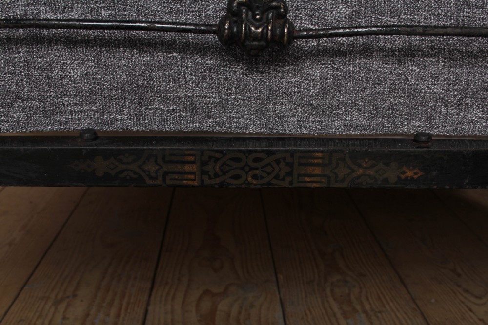 An antique dark wrought iron double bed frame featuring arched headboard and footboard rails with decorative cast rosettes. View III