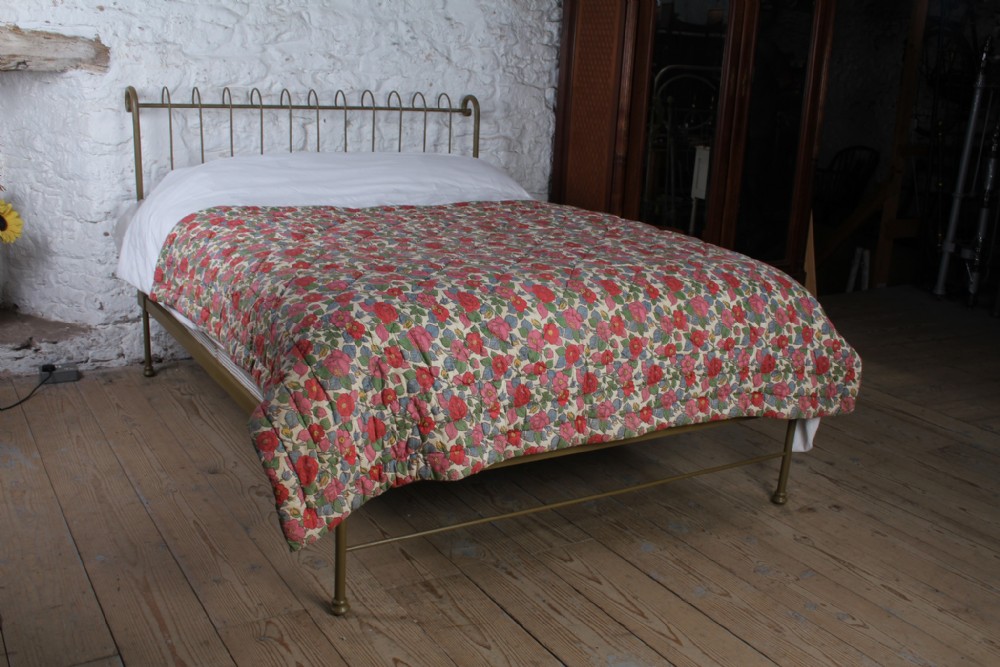 A forged iron king-size bedstead featuring an arched looped headboard and an open footless frame.