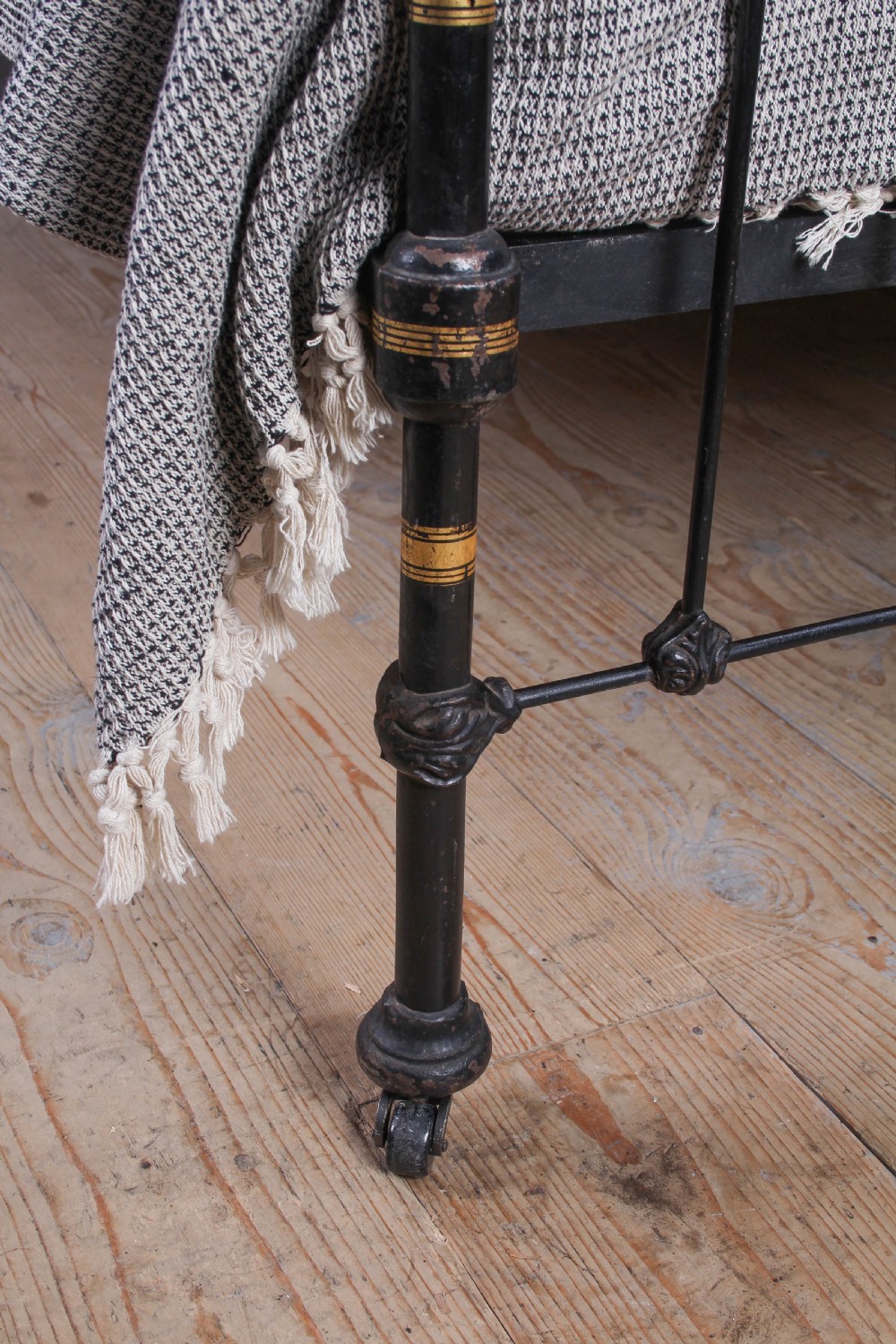 A Victorian five-foot king-size bedstead featuring a black japanned cast iron frame with vertical arched spindles, central diamond motifs, and brass top rails with brass finials. View VI