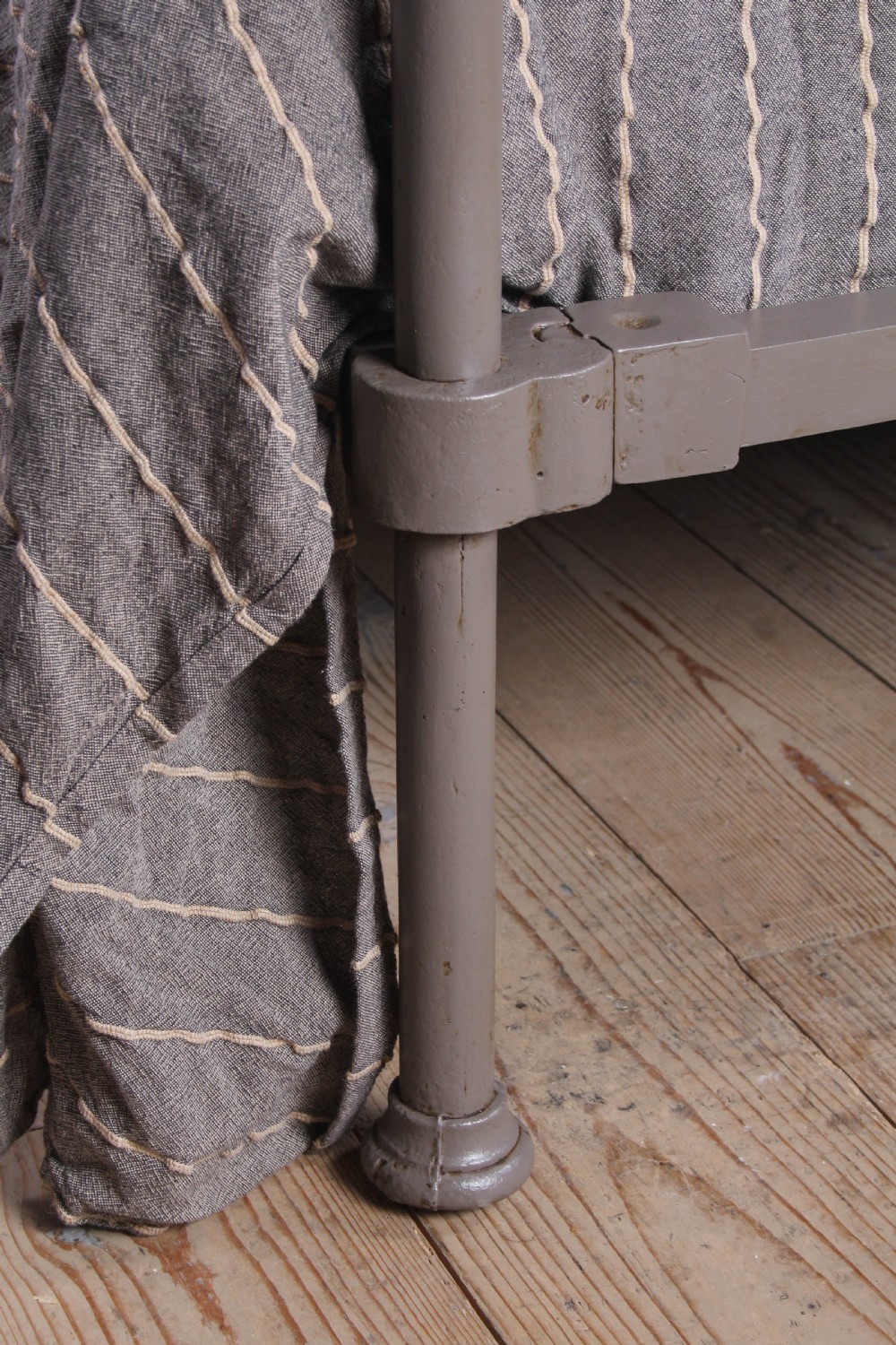 A low height king size metal four poster bed frame with slender corner posts, brass finials, and an arched headboard with vertical iron spindles. View V