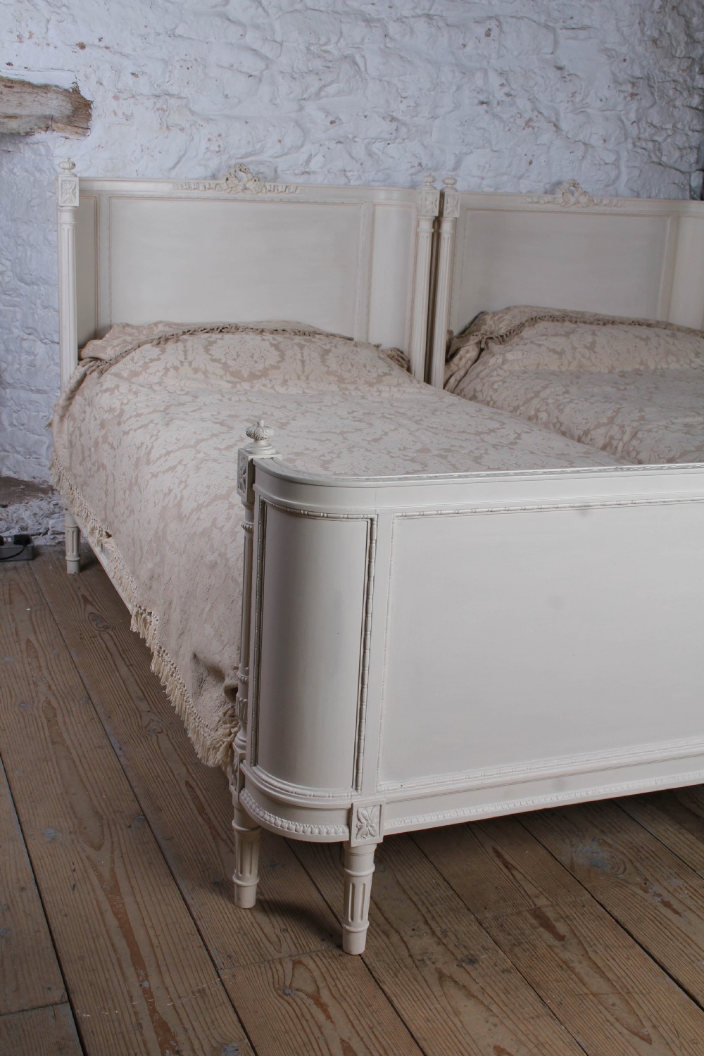 A pair of off-white painted French corbeille single bed frames featuring curved footboards, carved details, and fluted legs. View III