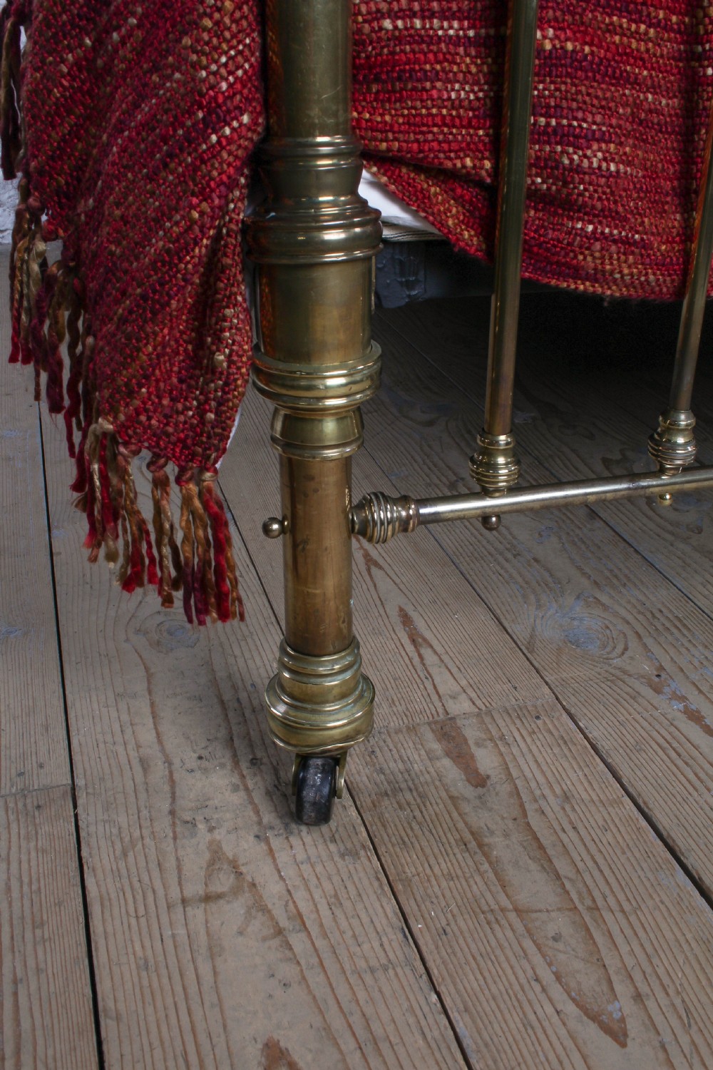 A Victorian brass king-size bed frame featuring turned upright posts, urn finials, vertical decorative spindles, circular roundels, and original castors. View VIII