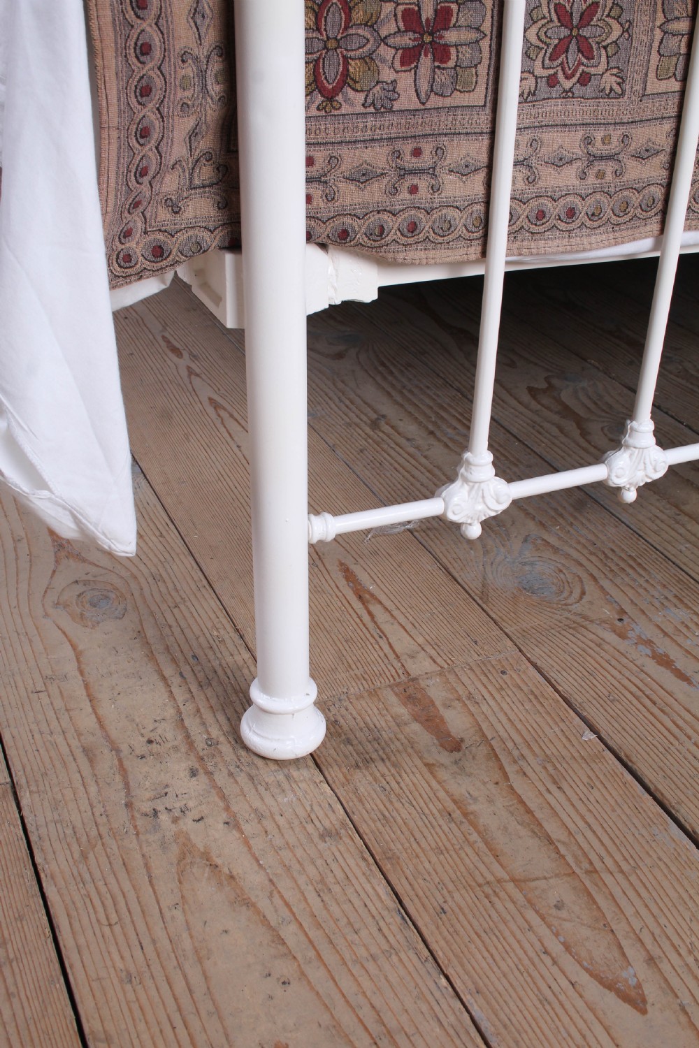 A Victorian white painted iron bedstead featuring brass top rails and brass urn finials on the headboard and footboard. View VI