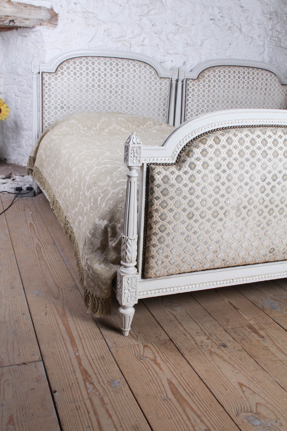 A pair of off-white painted French Empire style single bed frames featuring upholstered arched headboards and matching footboards with geometric fabric. View IV