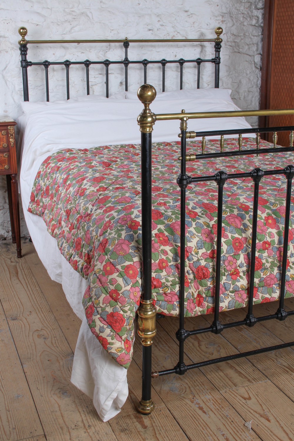 A Victorian double bedstead featuring a black painted cast iron frame, brass top rails, and spherical brass finials. View V