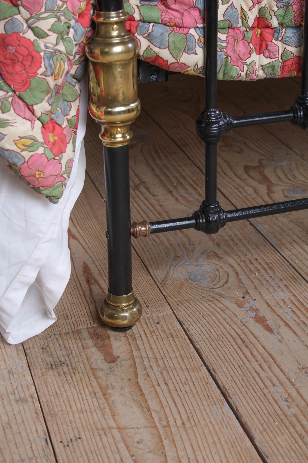 A Victorian double bedstead featuring a black painted cast iron frame, brass top rails, and spherical brass finials. View IX