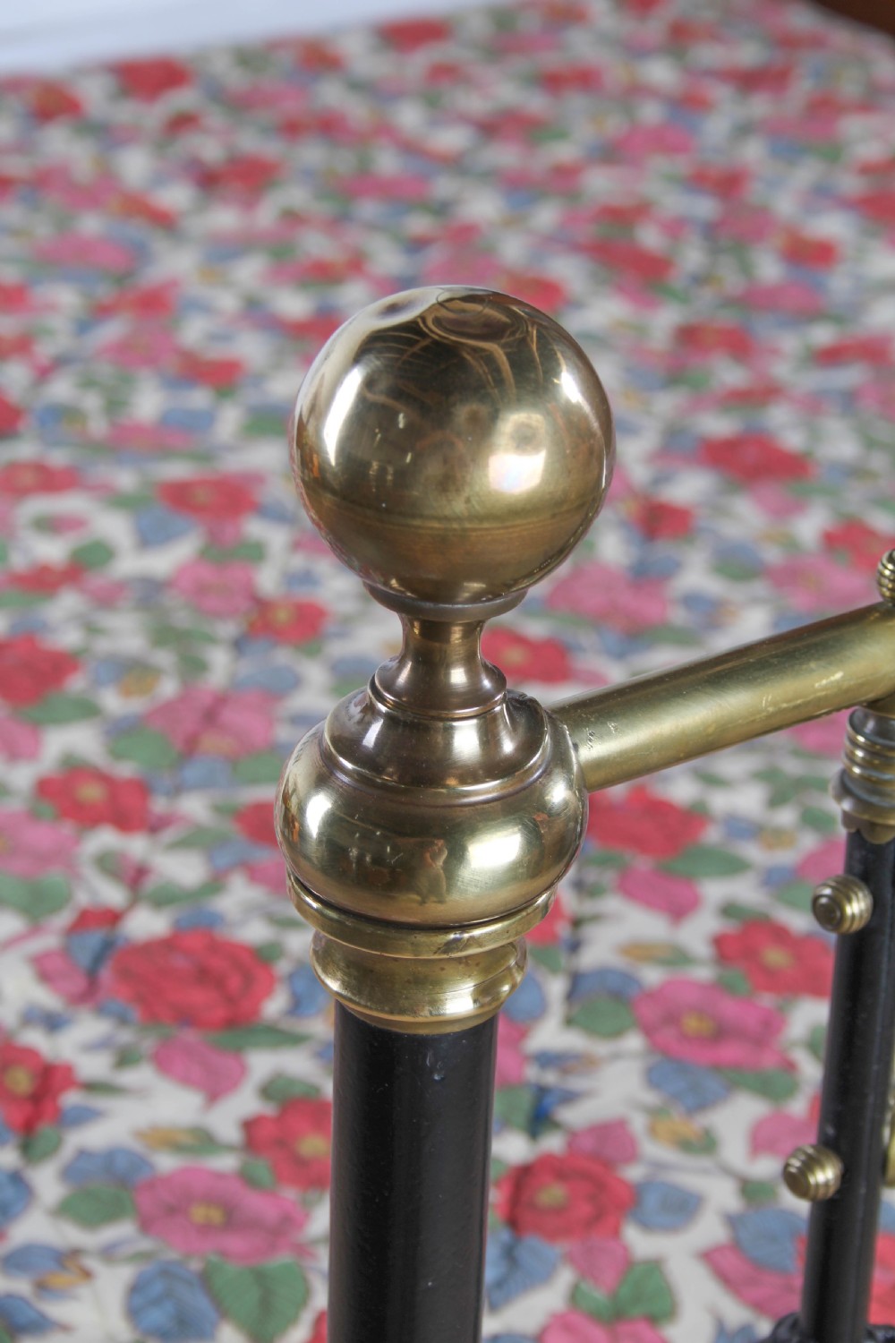 A Victorian double bedstead featuring a black painted cast iron frame, brass top rails, and spherical brass finials. View X