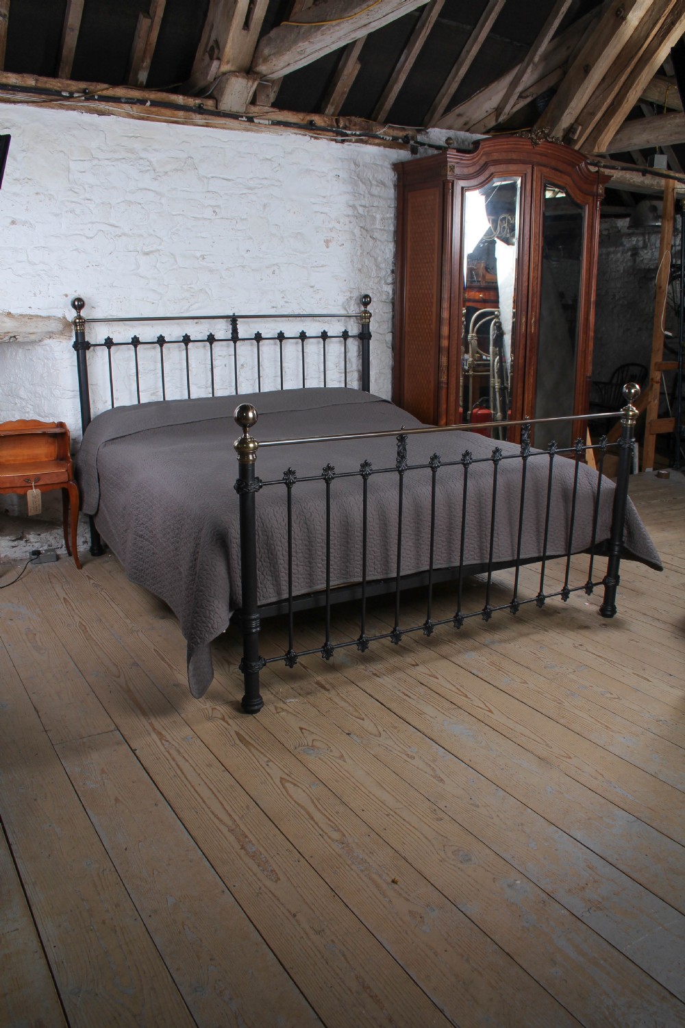 A super king size bedstead featuring a black iron frame with vertical spindles, cast rosettes, and brass top rails with brass ball finials. View III