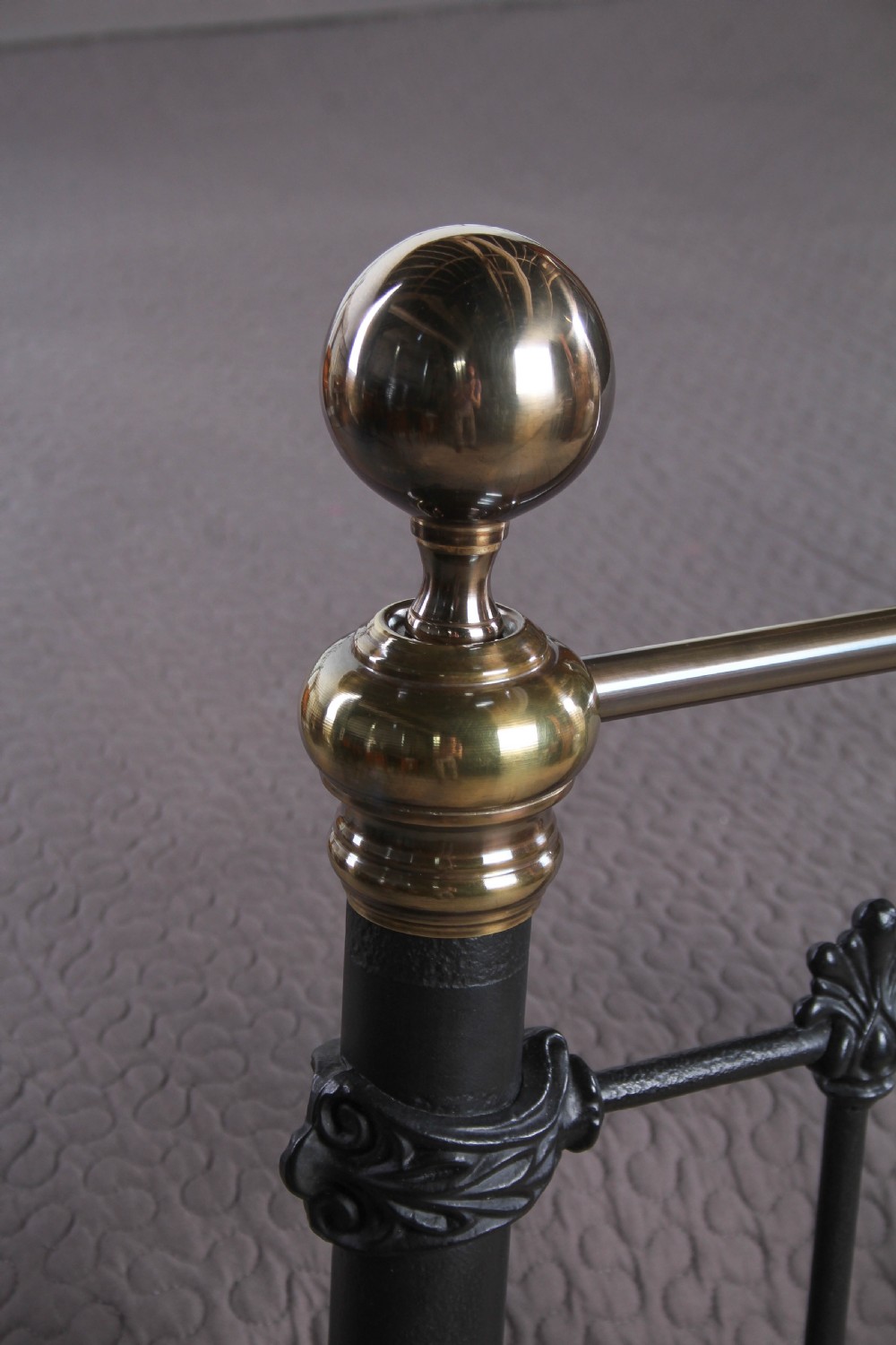 A super king size bedstead featuring a black iron frame with vertical spindles, cast rosettes, and brass top rails with brass ball finials. View VII