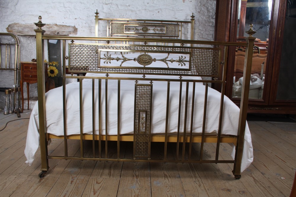 An antique French brass double bed frame with ornamental lattice headboard and footboard panels, vertical spindles, and finial corner posts. View II