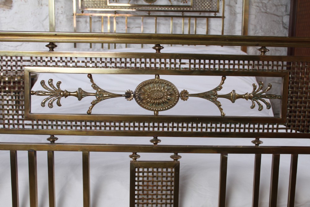 An antique French brass double bed frame with ornamental lattice headboard and footboard panels, vertical spindles, and finial corner posts. View III